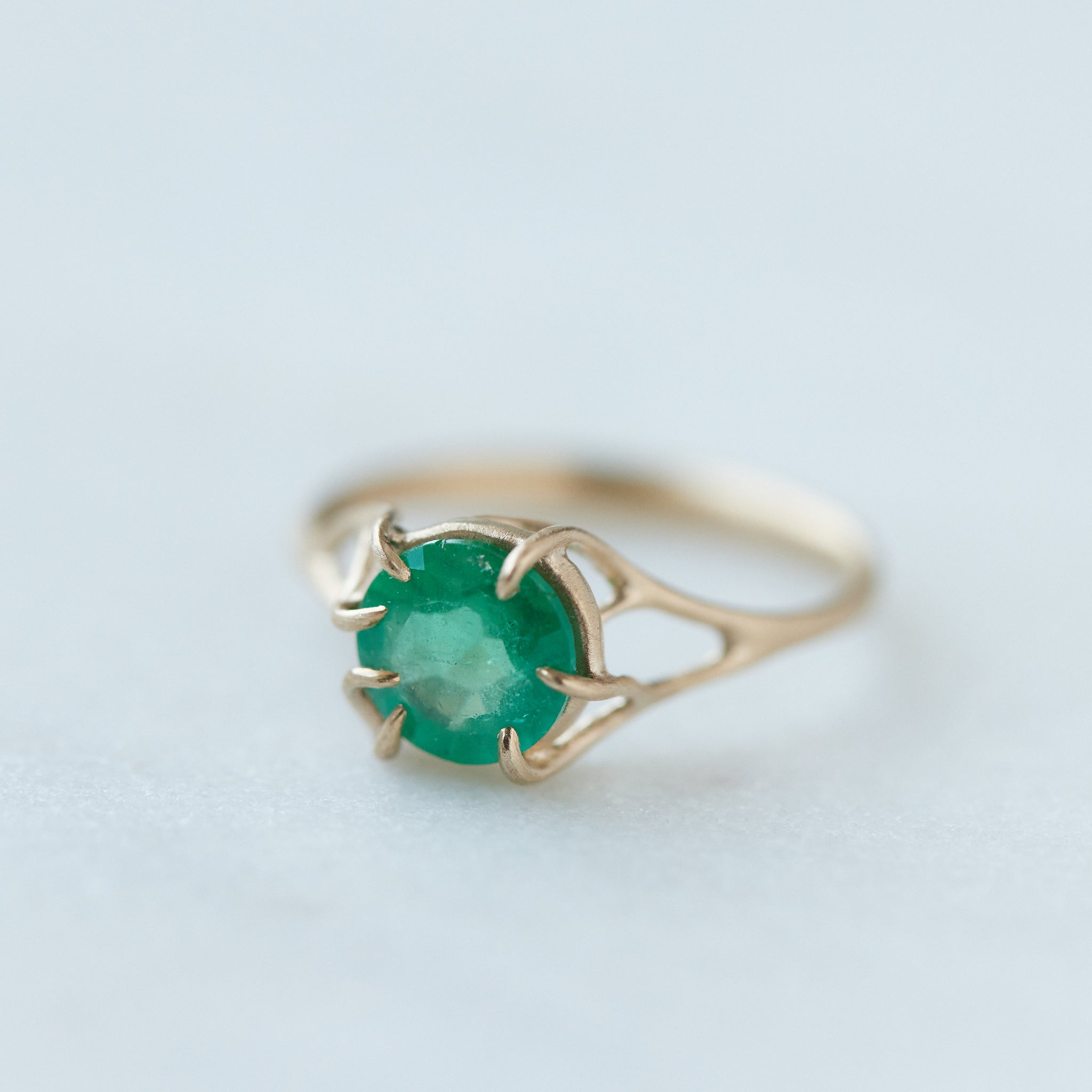 Round green emerald is set in a branch ring with branchy prongs holding the stone. Photographed on stone. 1/4 view.