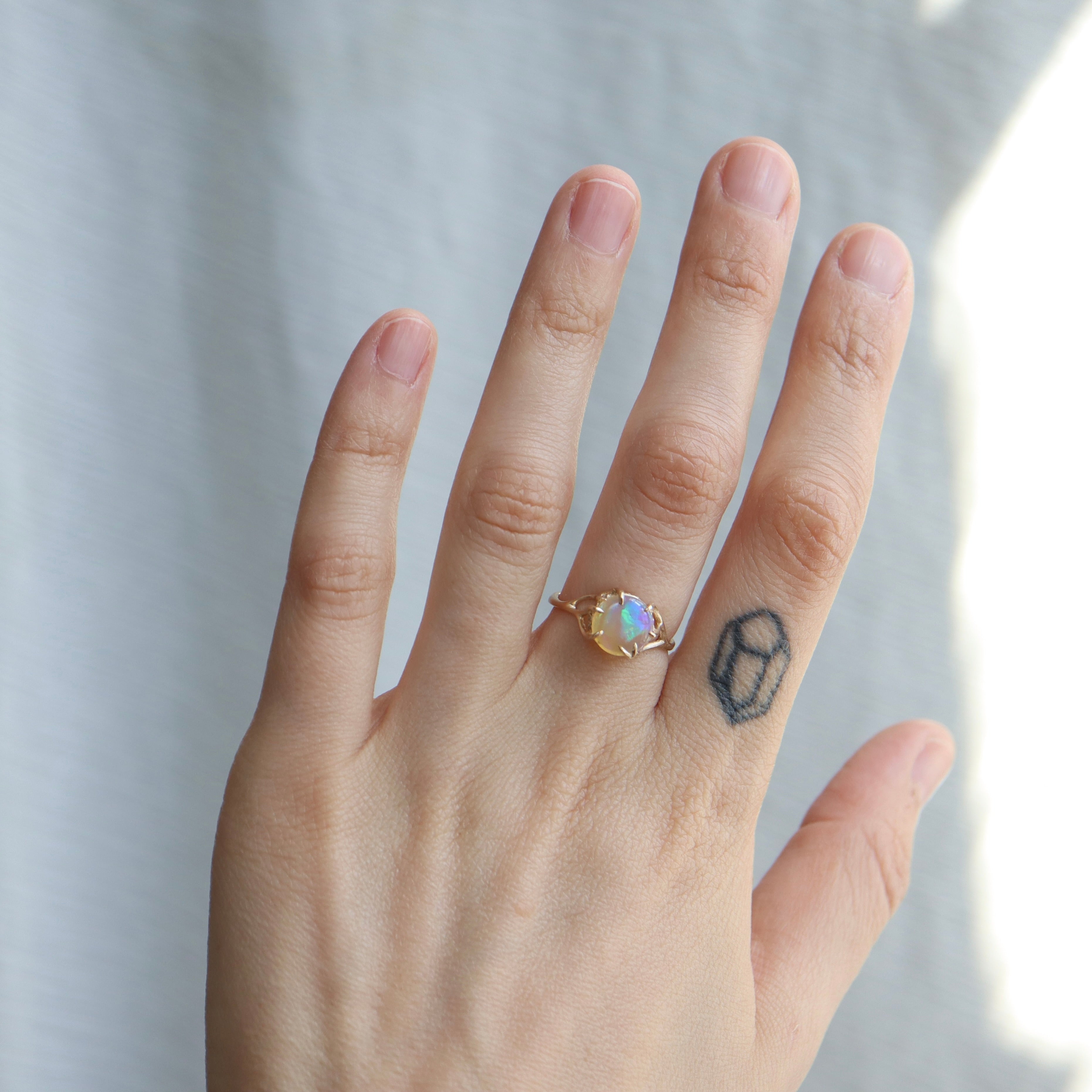 1.27ct Lightning Ridge Opal branch waiting ring set in 14k gold with a ring of modern melee diamonds, displayed on hand. 