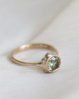 Gold ring with a green gemstone on a white fabric background