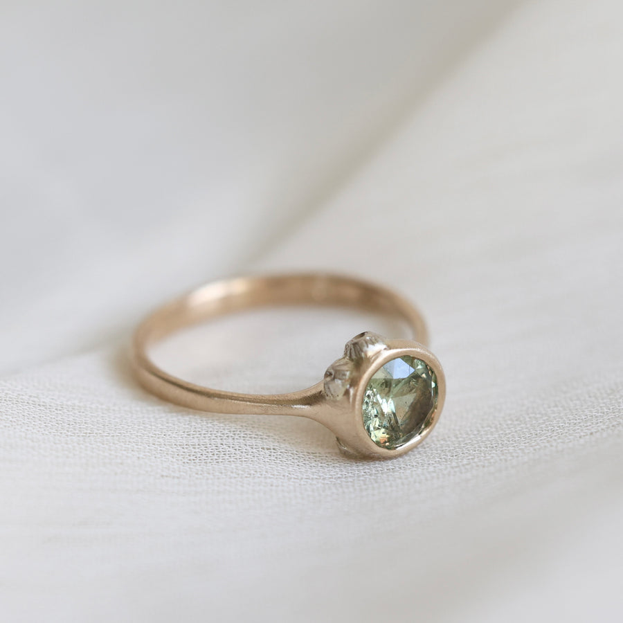 Gold ring with a green gemstone on a white fabric background