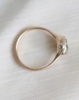 gold ring with a green stone on a white fabric background