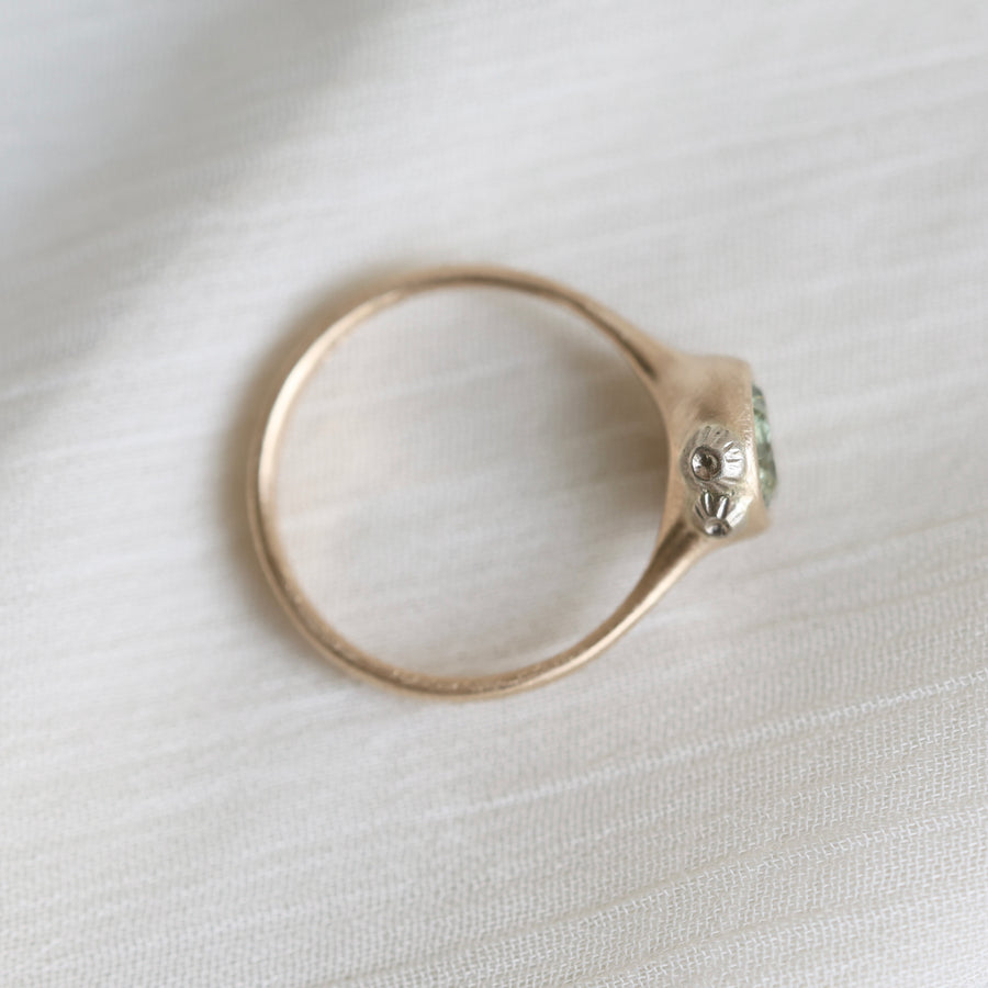 gold ring with a green stone on a white fabric background