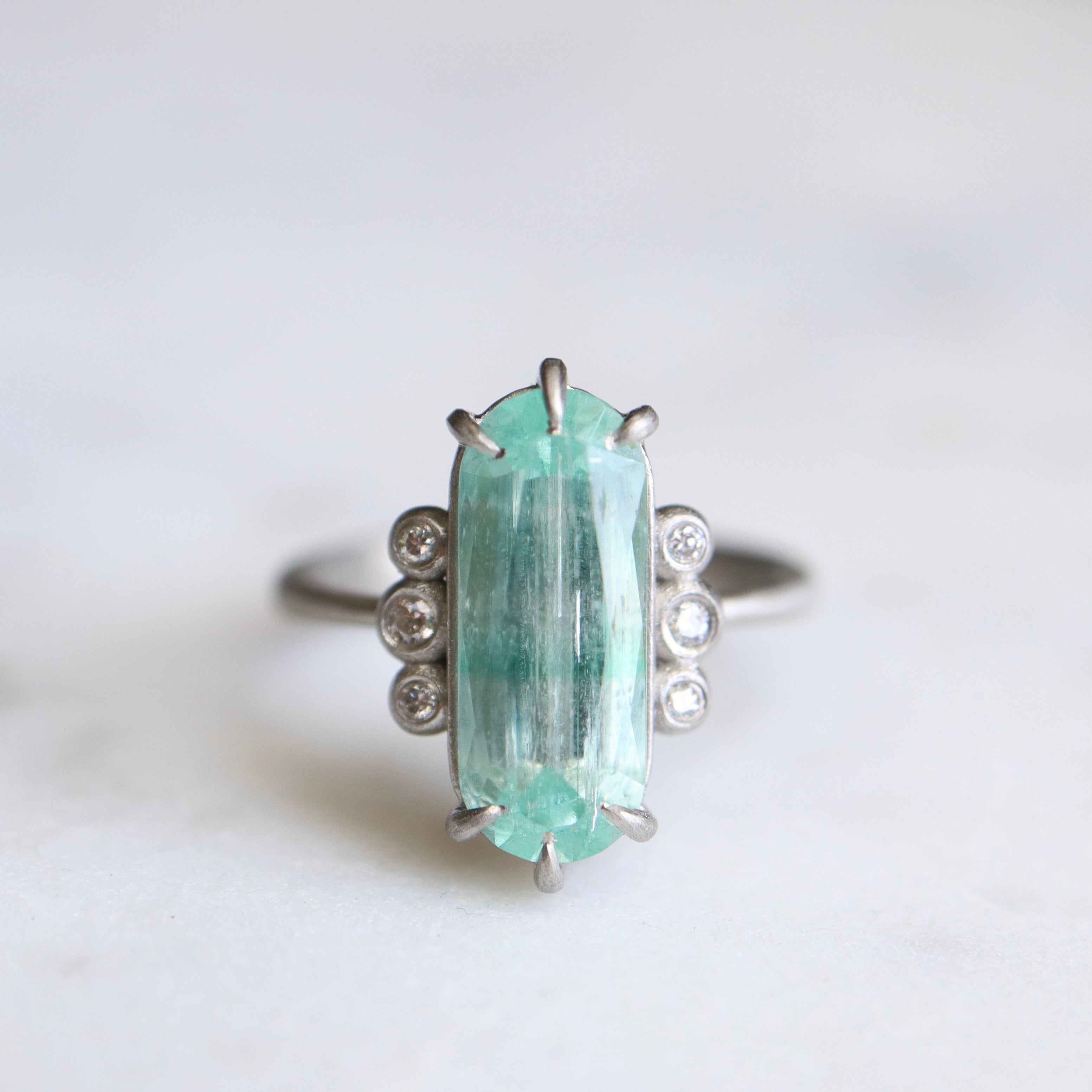 oval emerald center stone with three diamonds on each side. set in platinum.