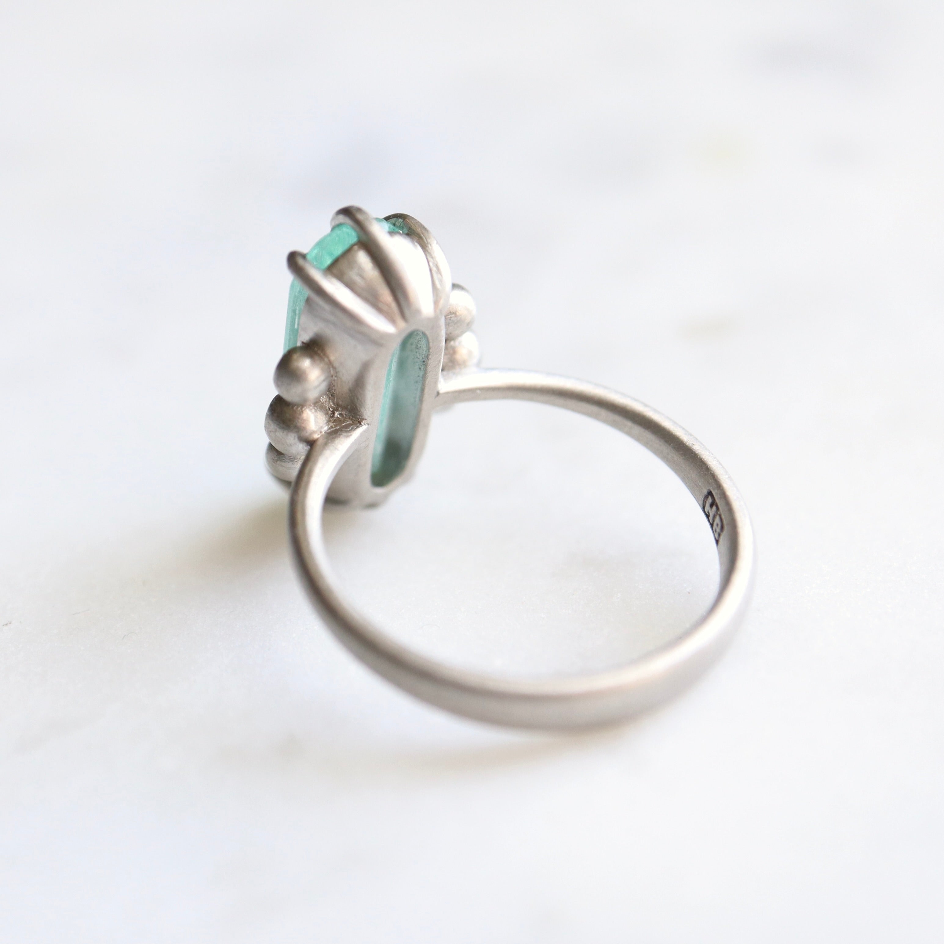 oval emerald center stone with three diamonds on each side. set in platinum. back view.