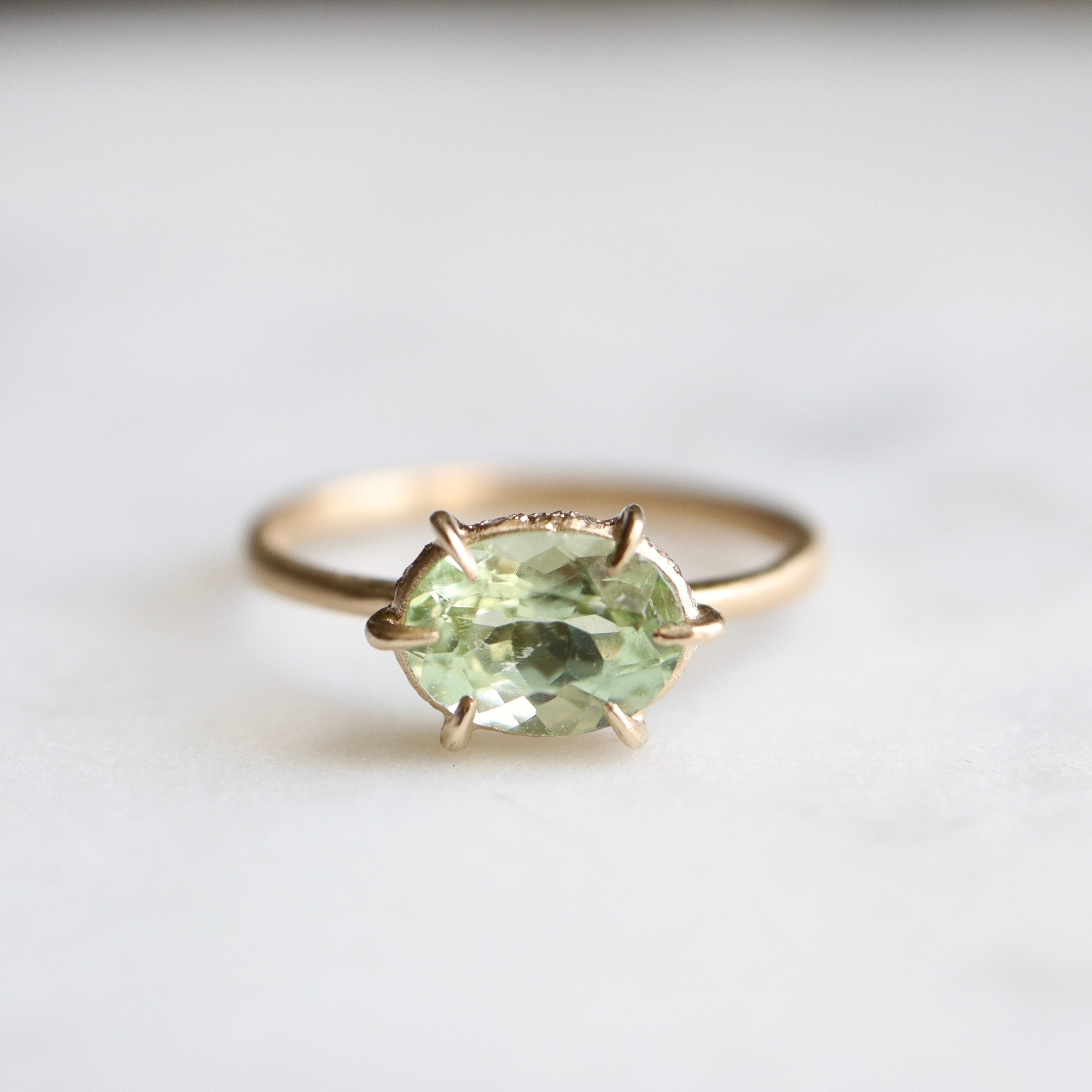 green oval tourmaline ring with gold prongs.