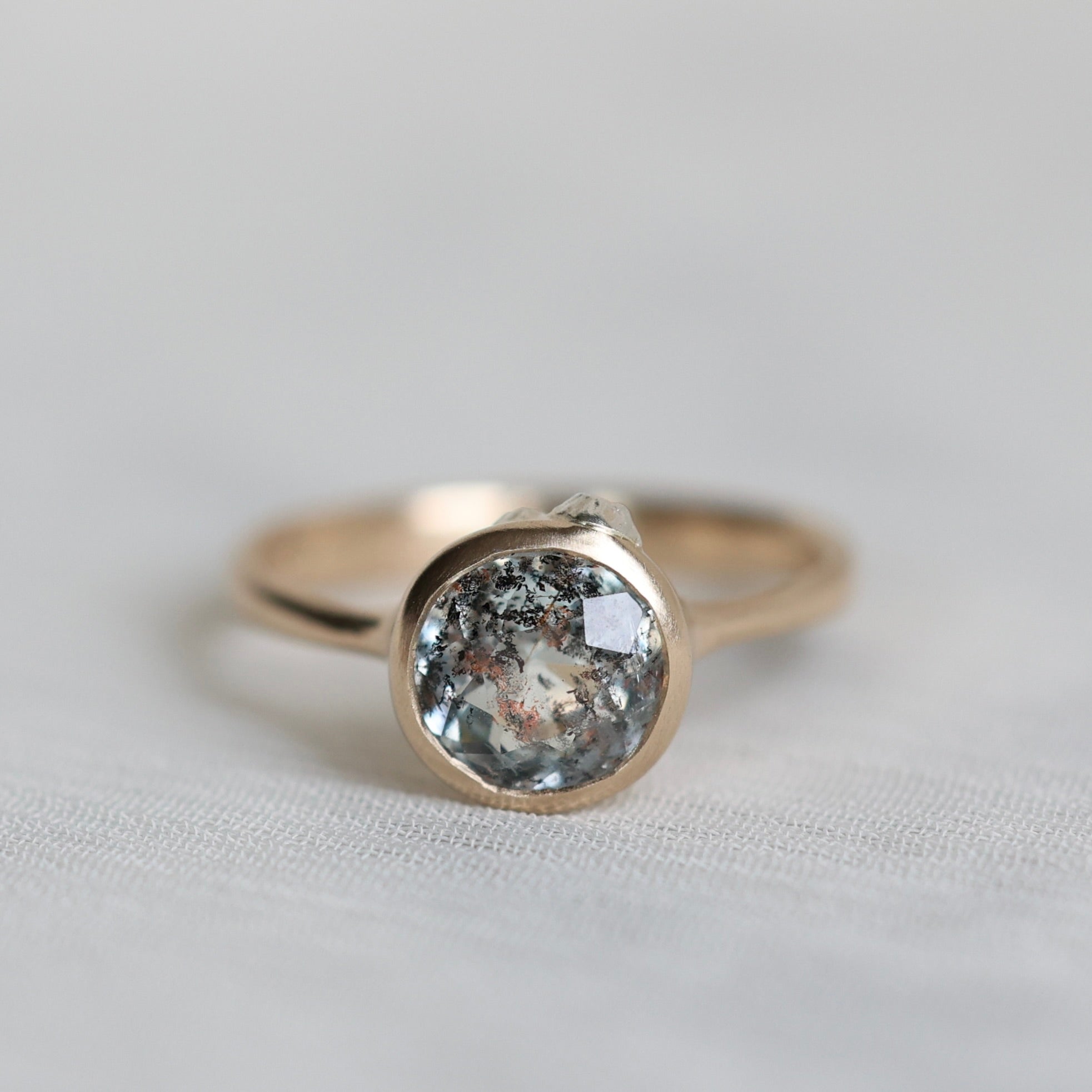 Gold ring with a round gemstone on a light gray background