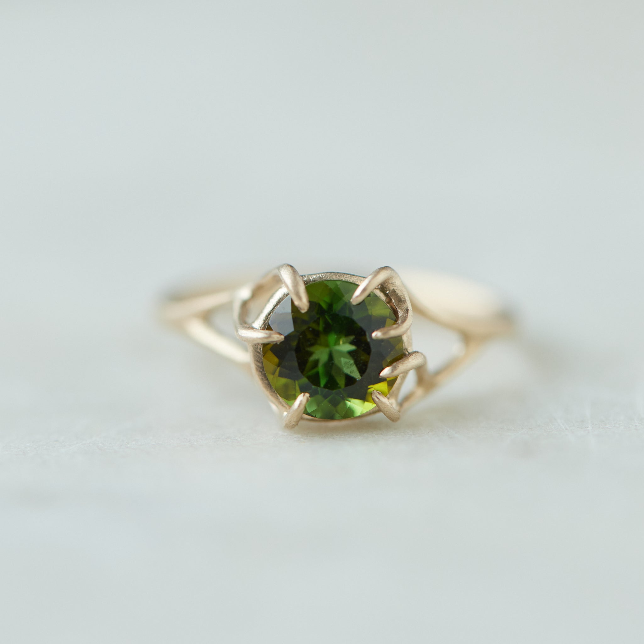 a lush green round tourmaline sits in gold branch prongs in this branch ring. front view.