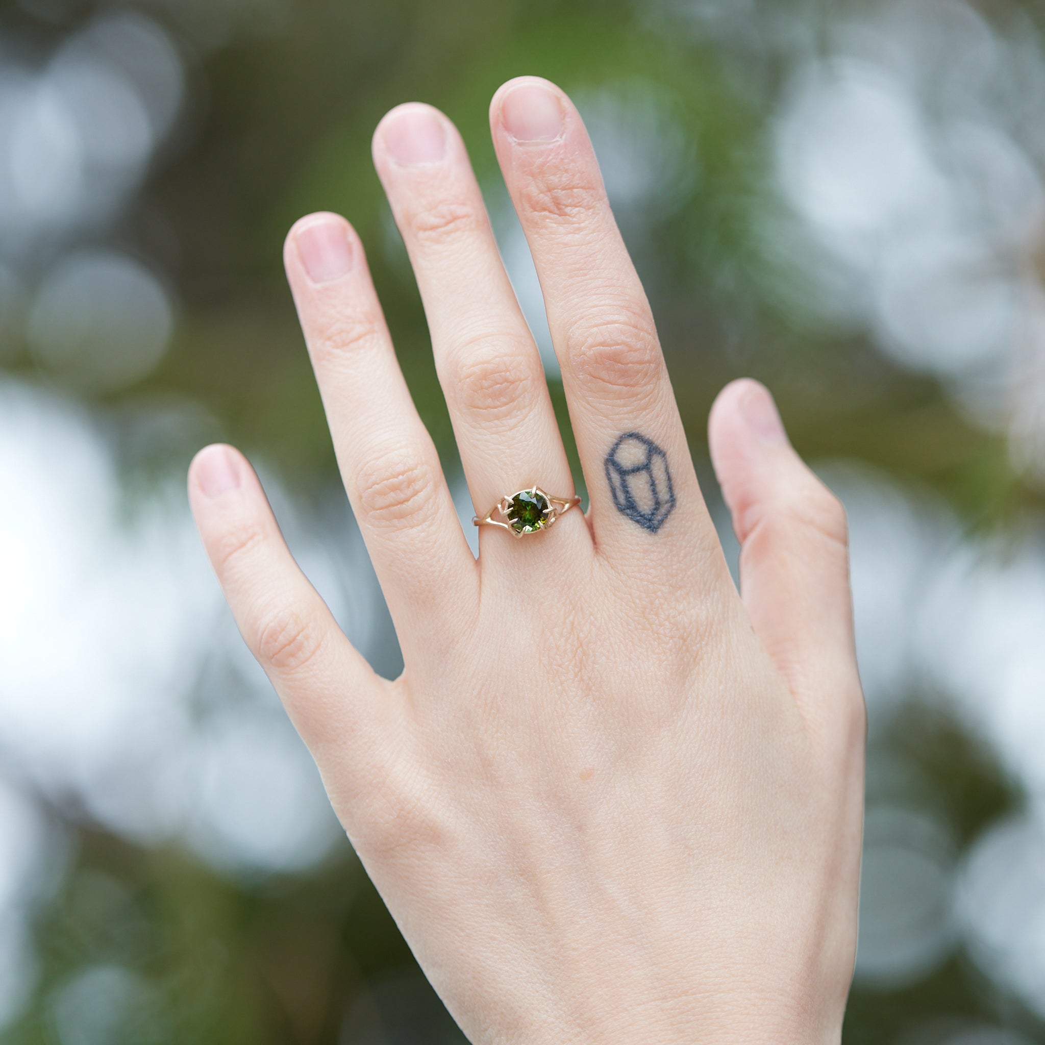 a lush green round tourmaline sits in gold branch prongs in this branch ring. shown on hand