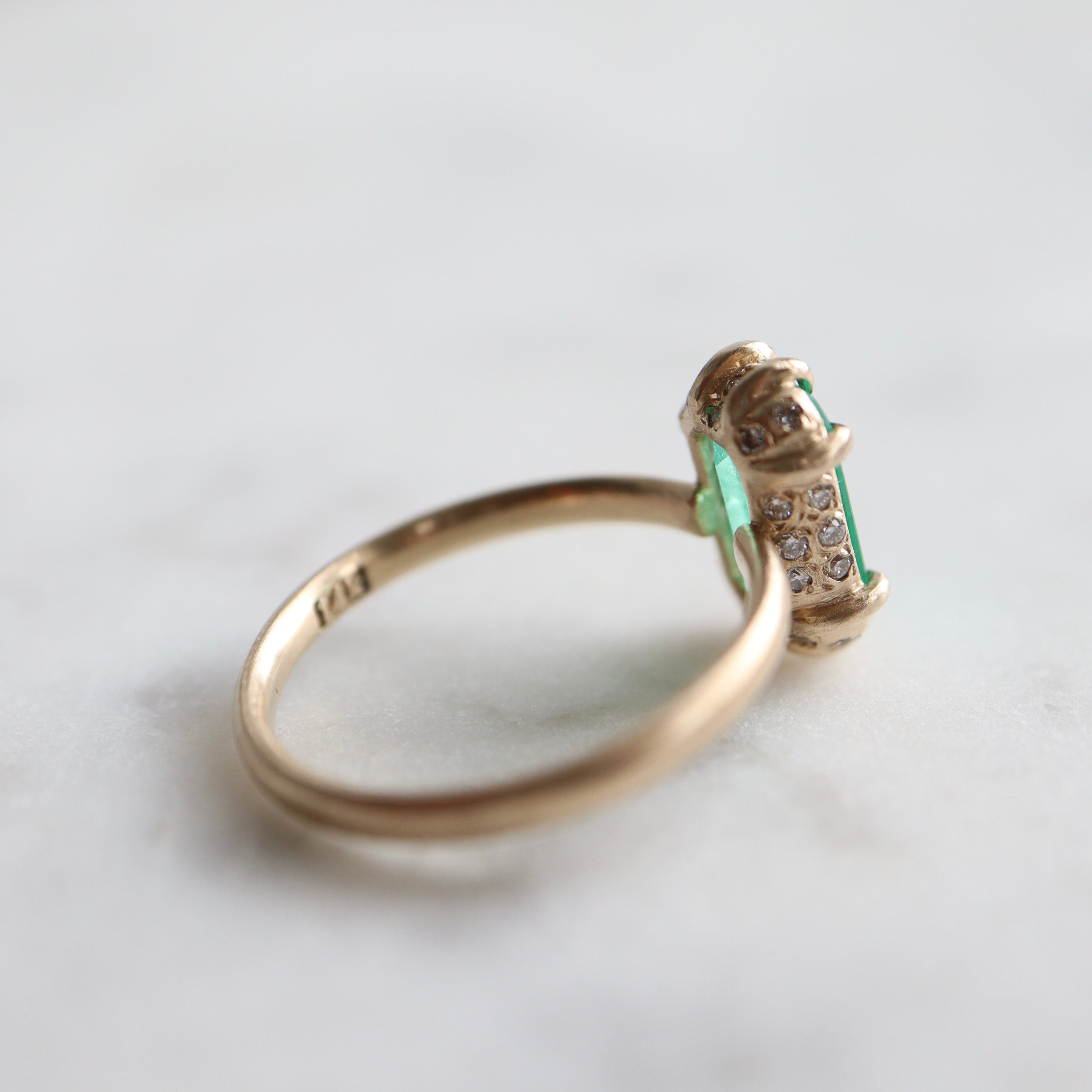 green emerald retangular stone set in gold ring with prongs- side profile to show the diamonds