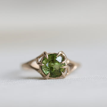 gold ring with green gemstone on pale fabric