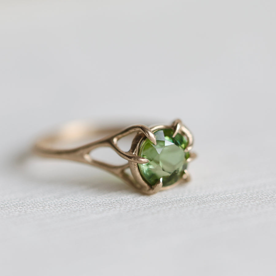 gold ring with green gemstone on pale fabric