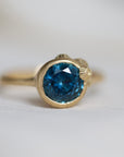 Gold ring with a blue gemstone on a light gray background