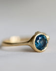 Gold ring with a blue gemstone on a light gray background