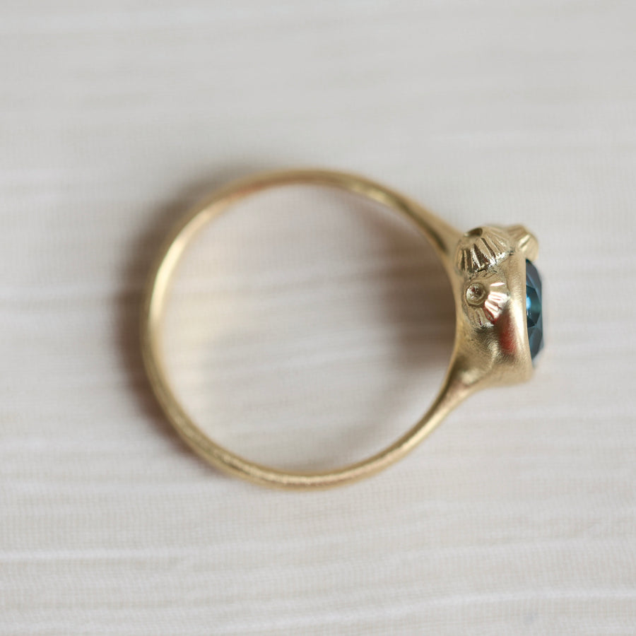 Gold ring with a blue gemstone on a white background
