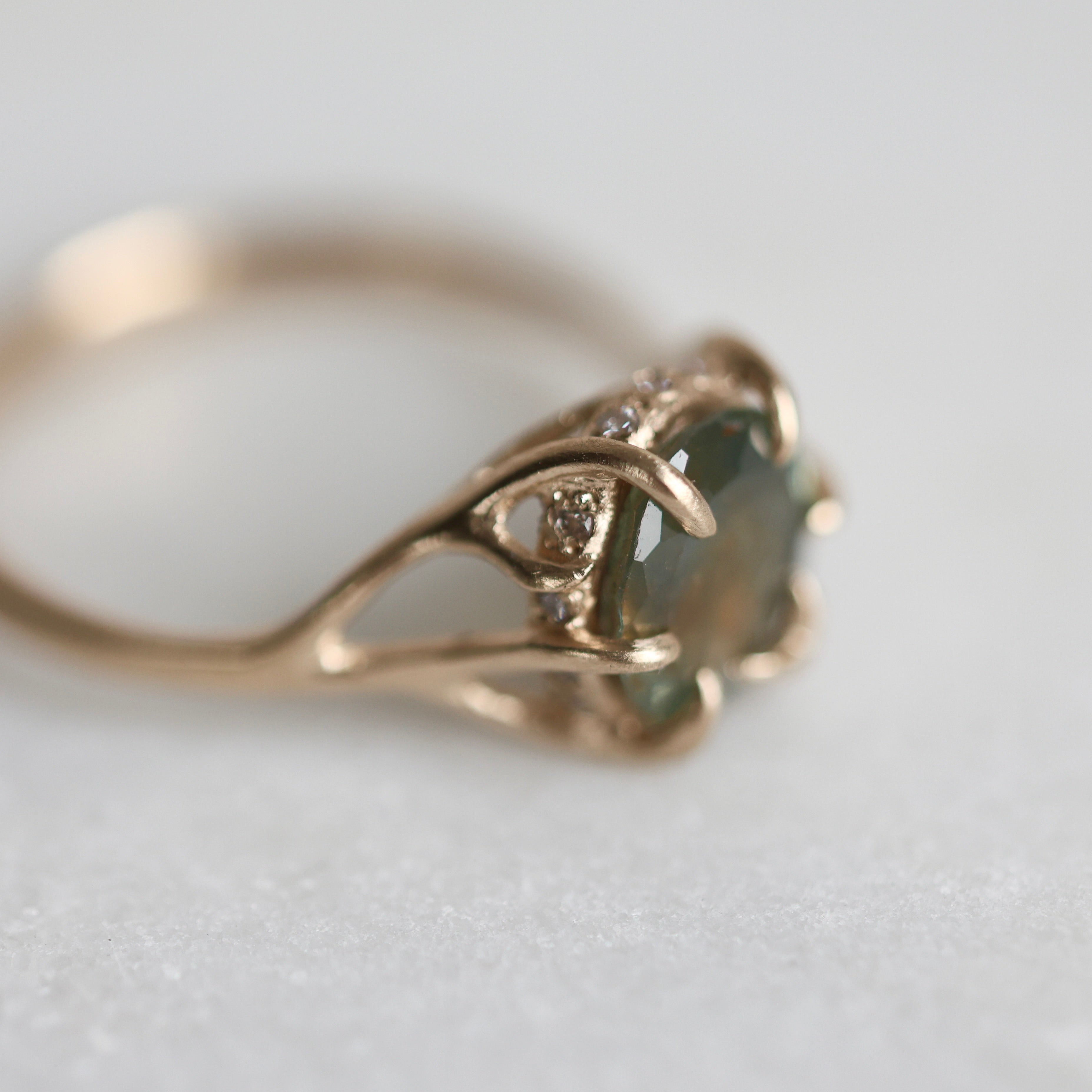 Gold ring with a multicolored gemstone on a light gray background