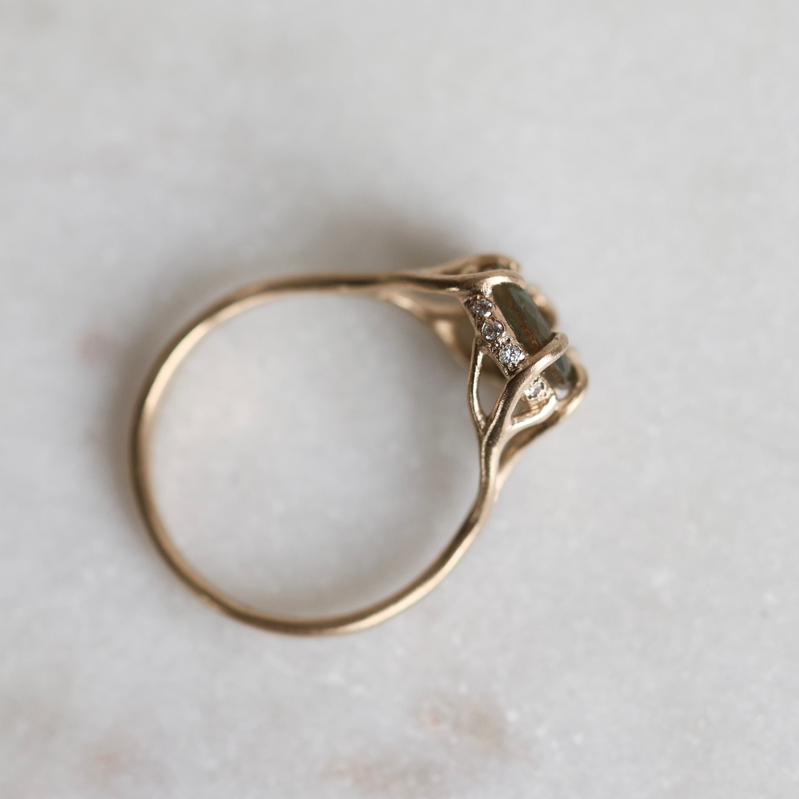 Gold ring with a multicolored gemstone on a light gray background