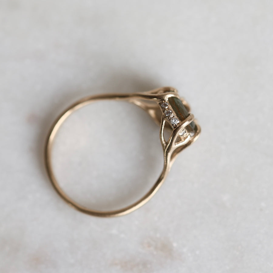 Gold ring with a multicolored gemstone on a light gray background