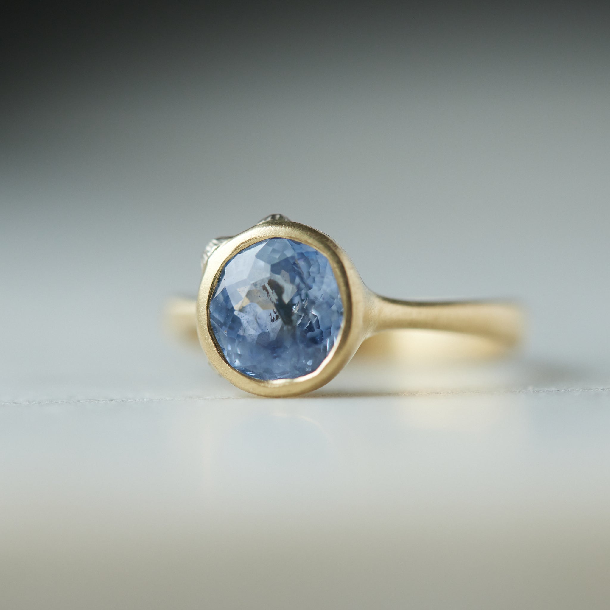 Periwinkle Montana sapphire in yellow gold bezel setting with hand-carved barnacles