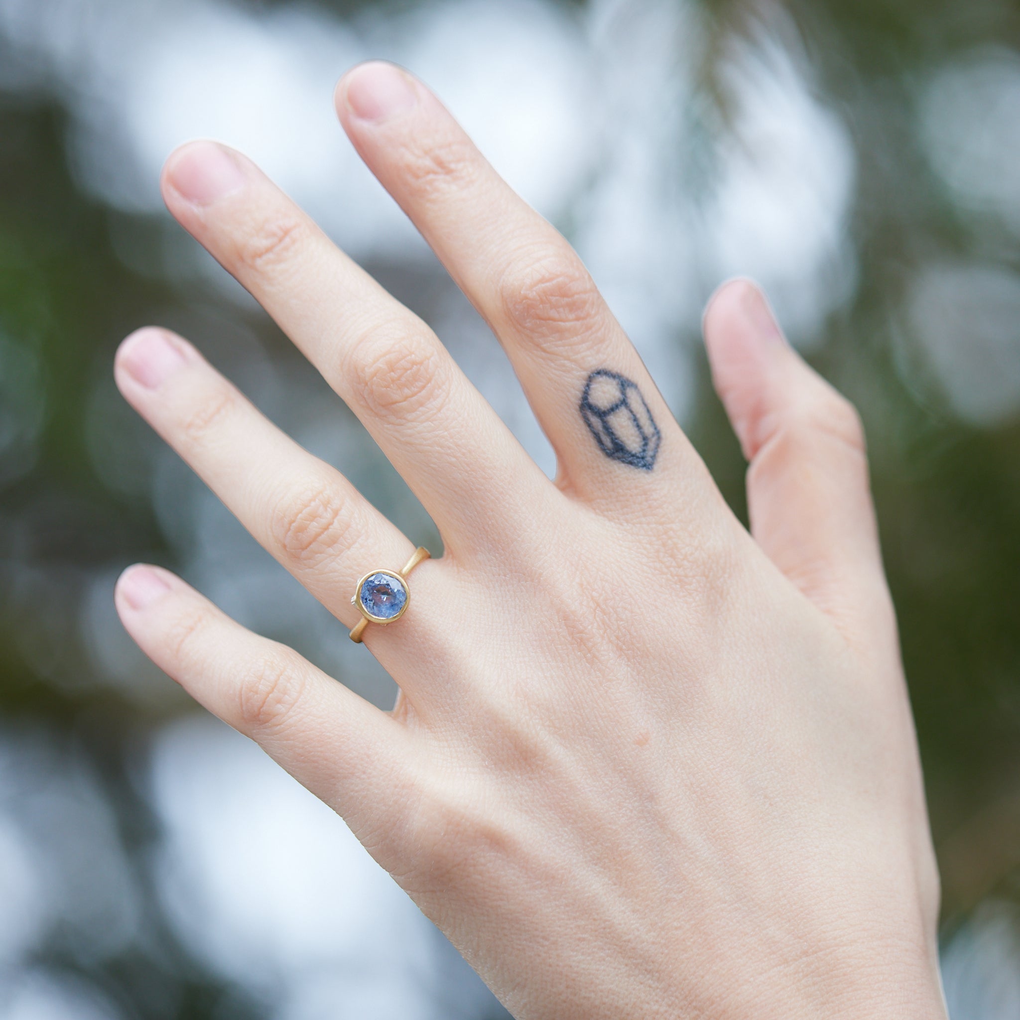 Periwinkle Montana sapphire in yellow gold bezel setting with hand-carved barnacles on person