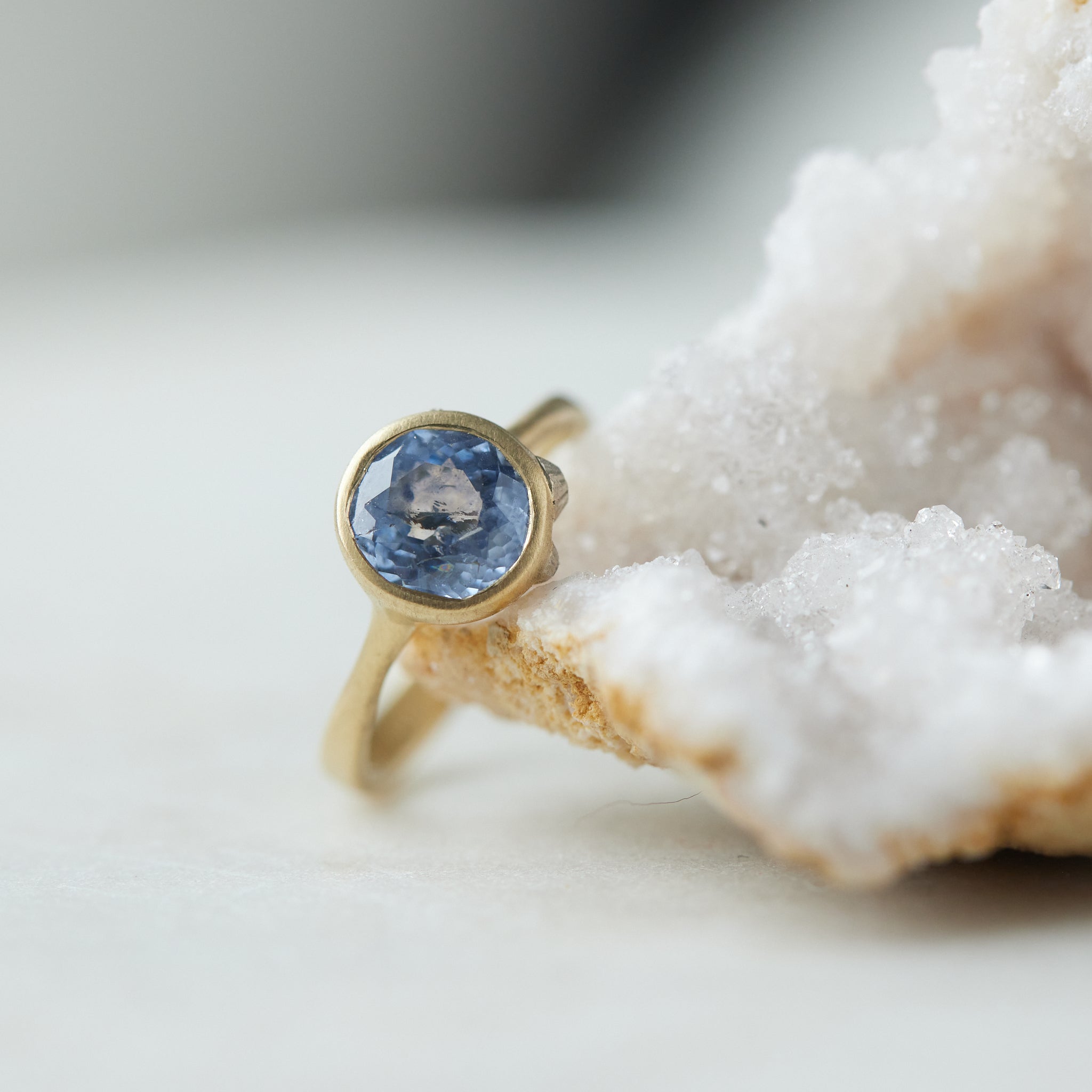 Periwinkle Montana sapphire in yellow gold bezel setting with hand-carved barnacles