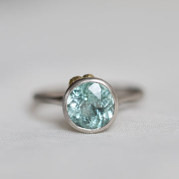 Silver ring with a light blue gemstone on a white background
