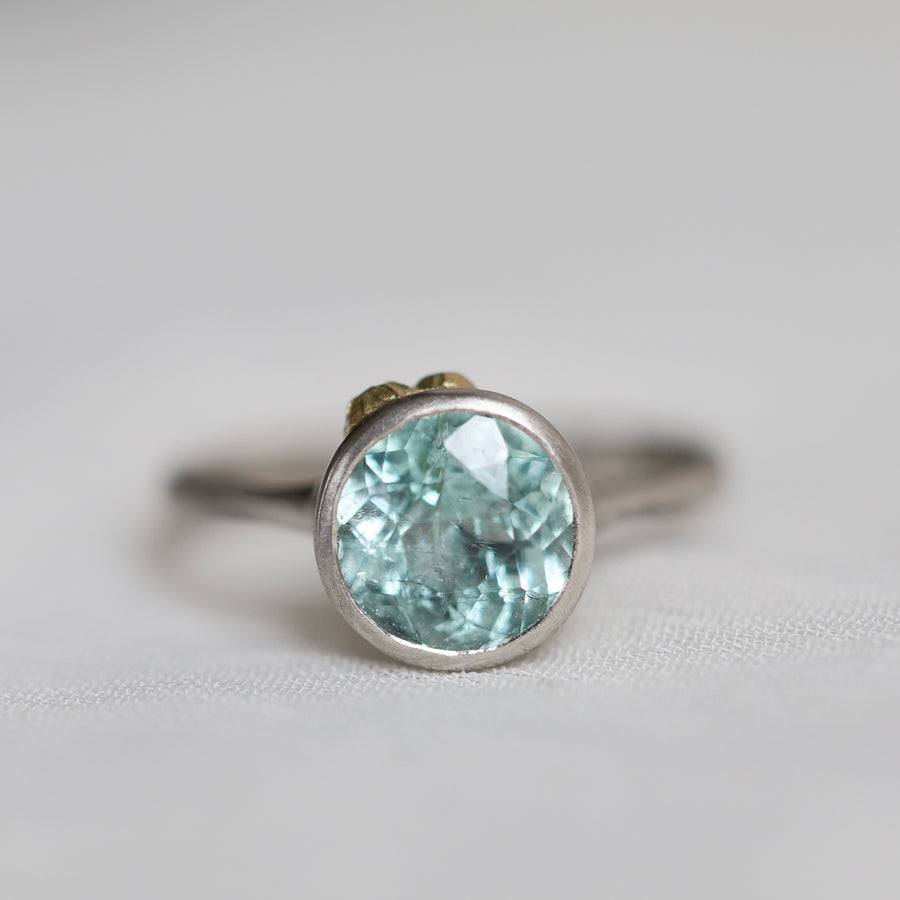 Silver ring with a light blue gemstone on a white background