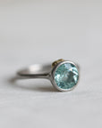 Silver ring with a light blue gemstone on a light gray background