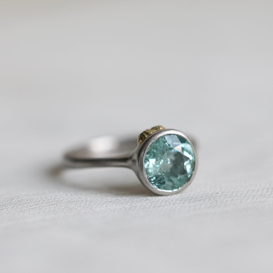 Silver ring with a light blue gemstone on a light gray background