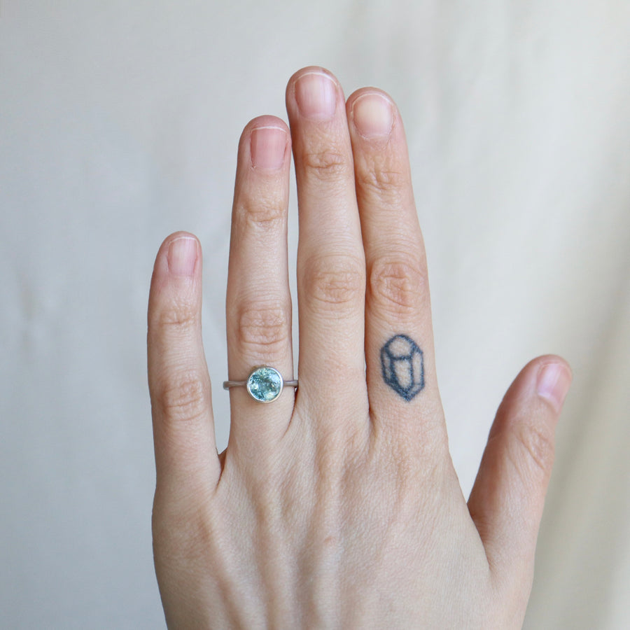 Hand with a ring and a small tattoo on a plain background