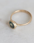 Gold ring with a blue gemstone on a light gray background