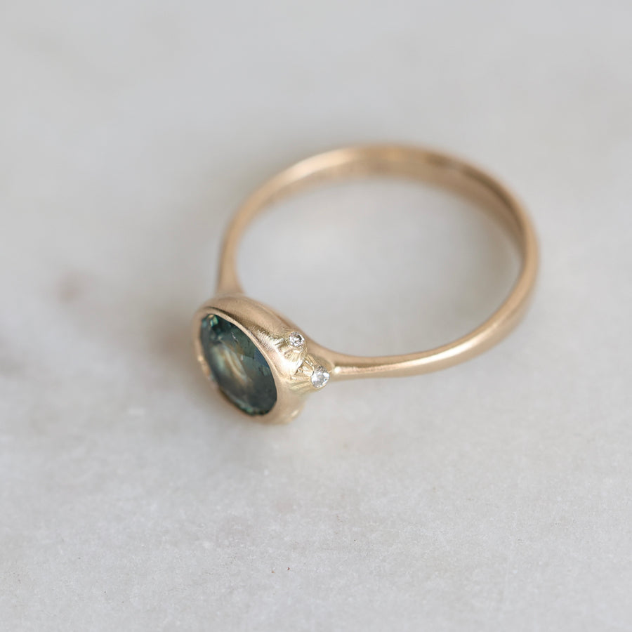 Gold ring with a blue gemstone on a light gray background