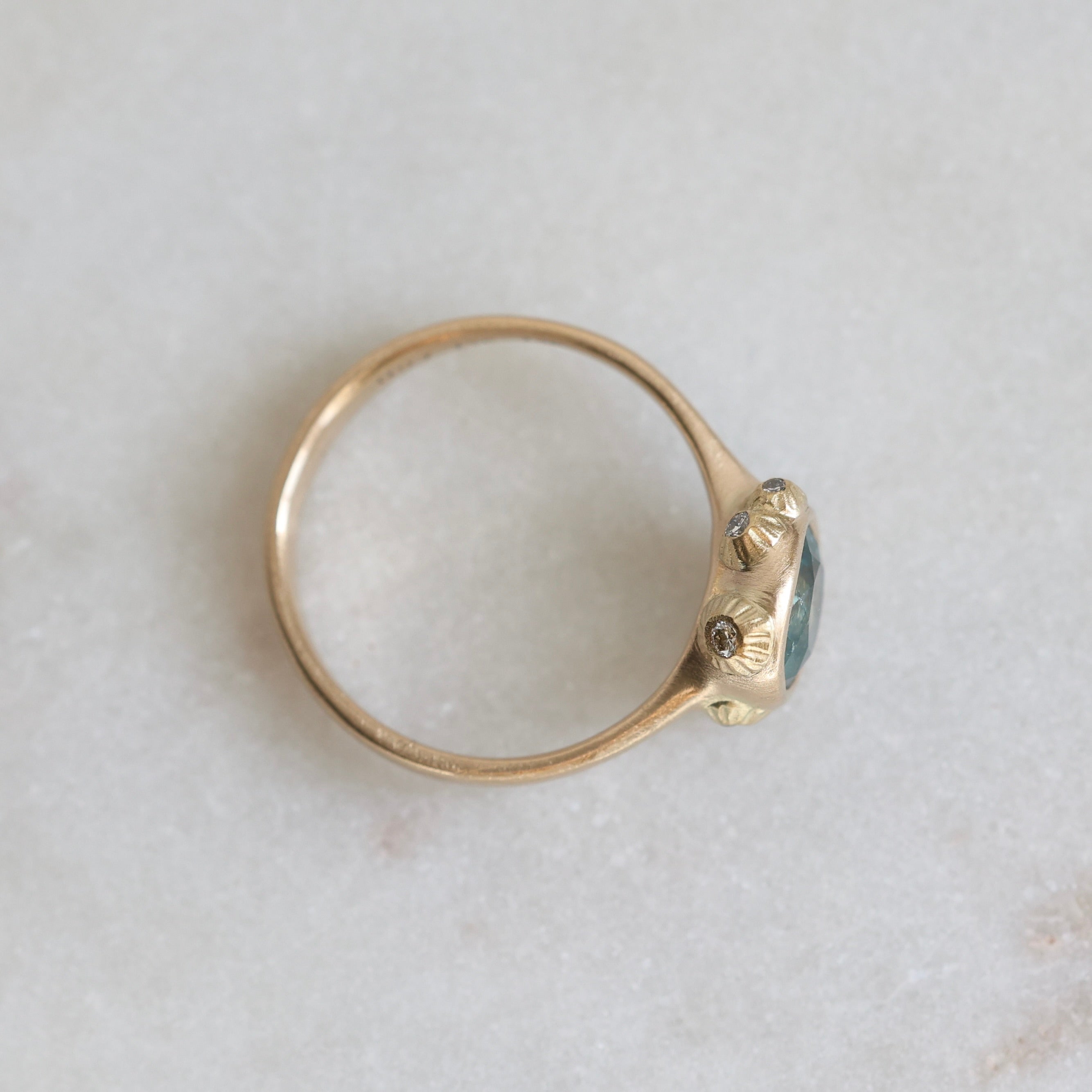Gold ring with a blue gemstone on a light gray background