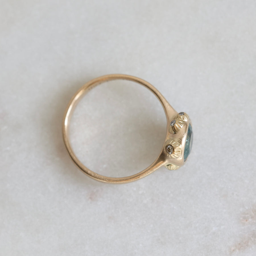 Gold ring with a blue gemstone on a light gray background