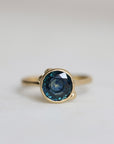 Gold ring with a blue gemstone on a light gray background