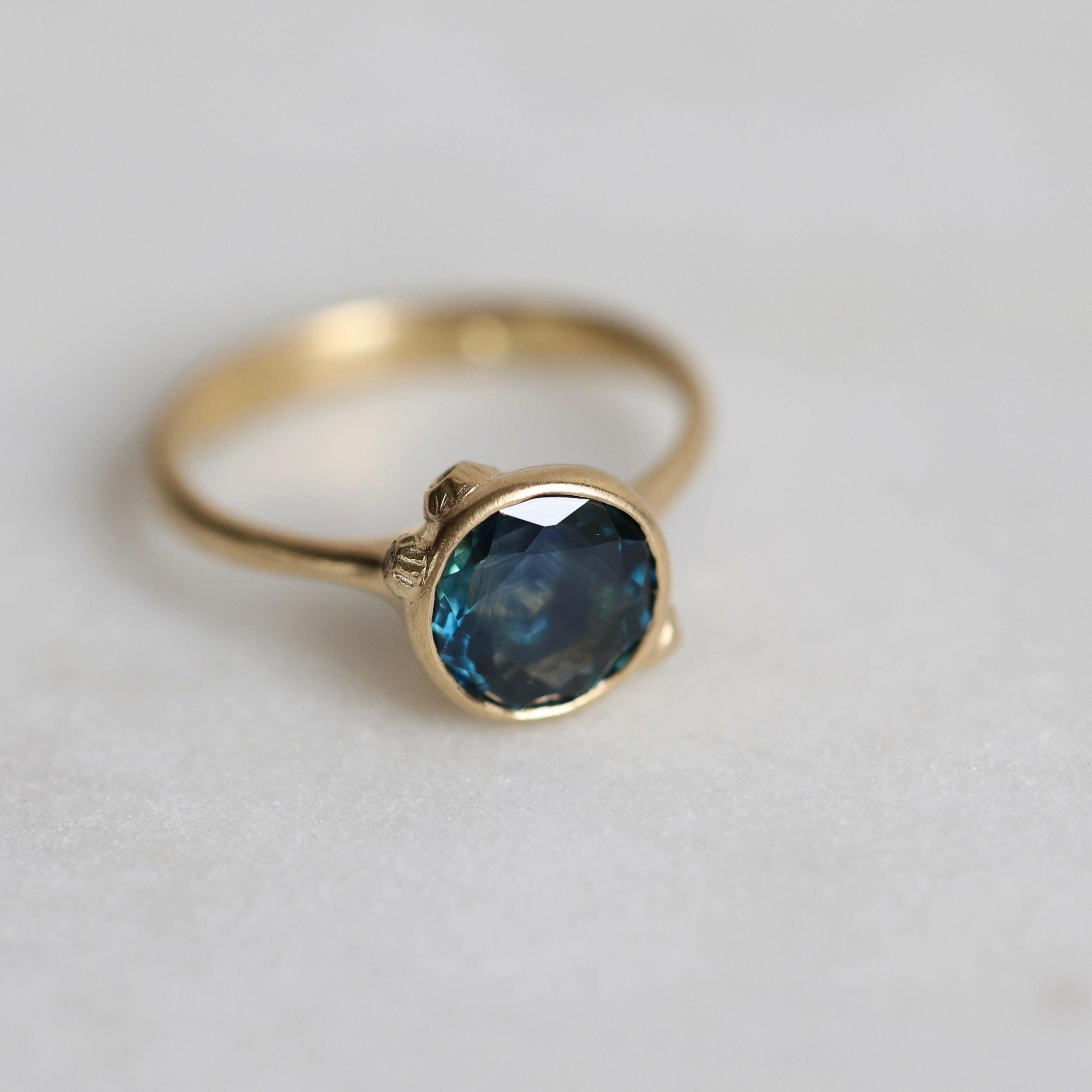 Gold ring with a blue gemstone on a light gray background