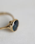 Gold ring with a blue gemstone on a light gray background