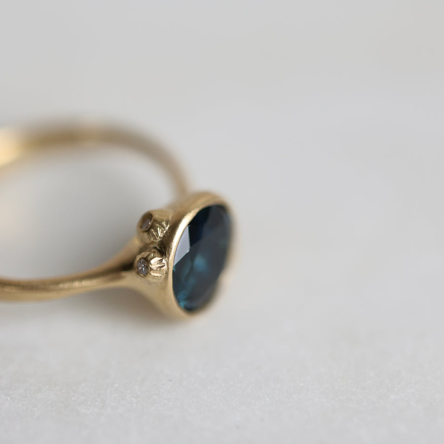 Gold ring with a blue gemstone on a light gray background