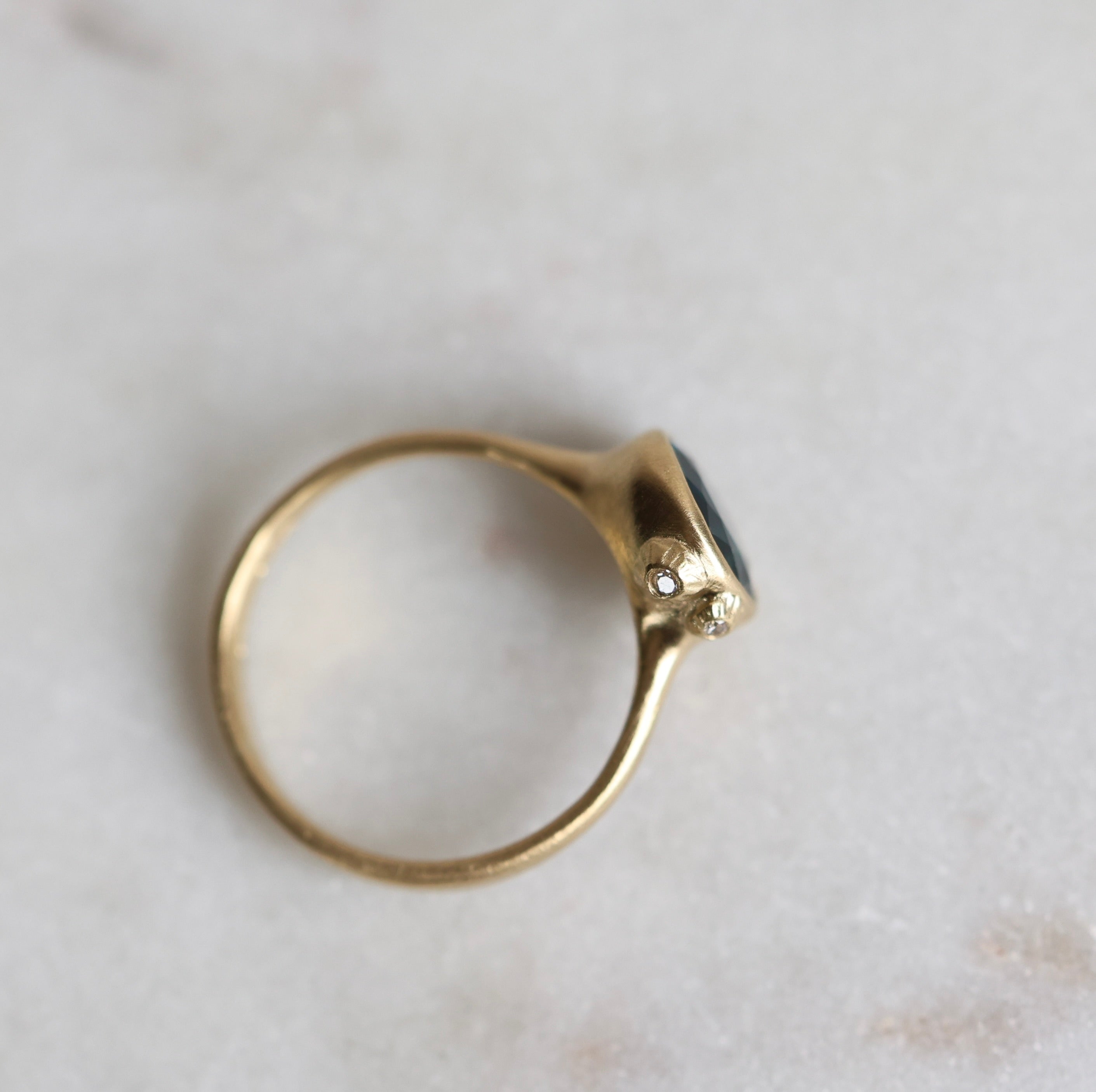 Gold ring with a blue stone on a light marble background