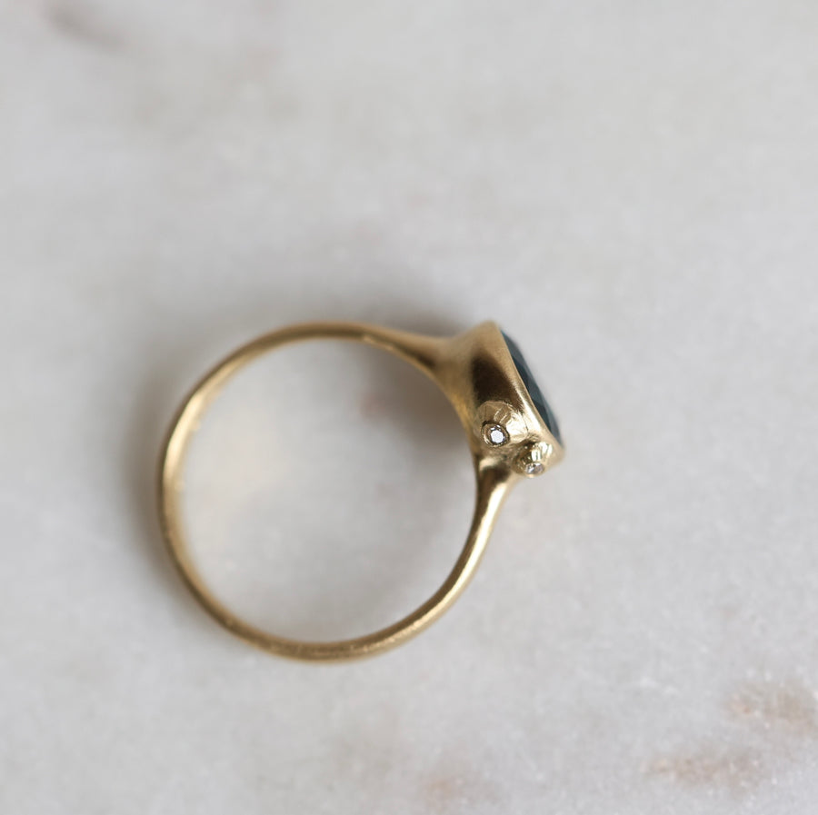 Gold ring with a blue stone on a light marble background