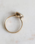 Gold ring with barnacles on a light marble background