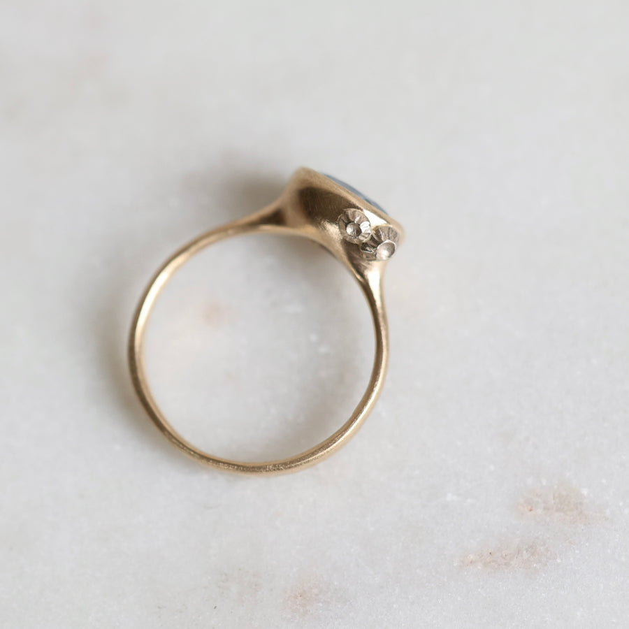 Gold ring with barnacles on a light marble background