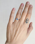 Hand wearing a ring with a gemstone on a plain background