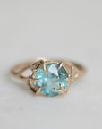 Gold ring with a blue gemstone on a light gray background