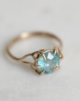 Gold ring with a blue gemstone on a light gray background