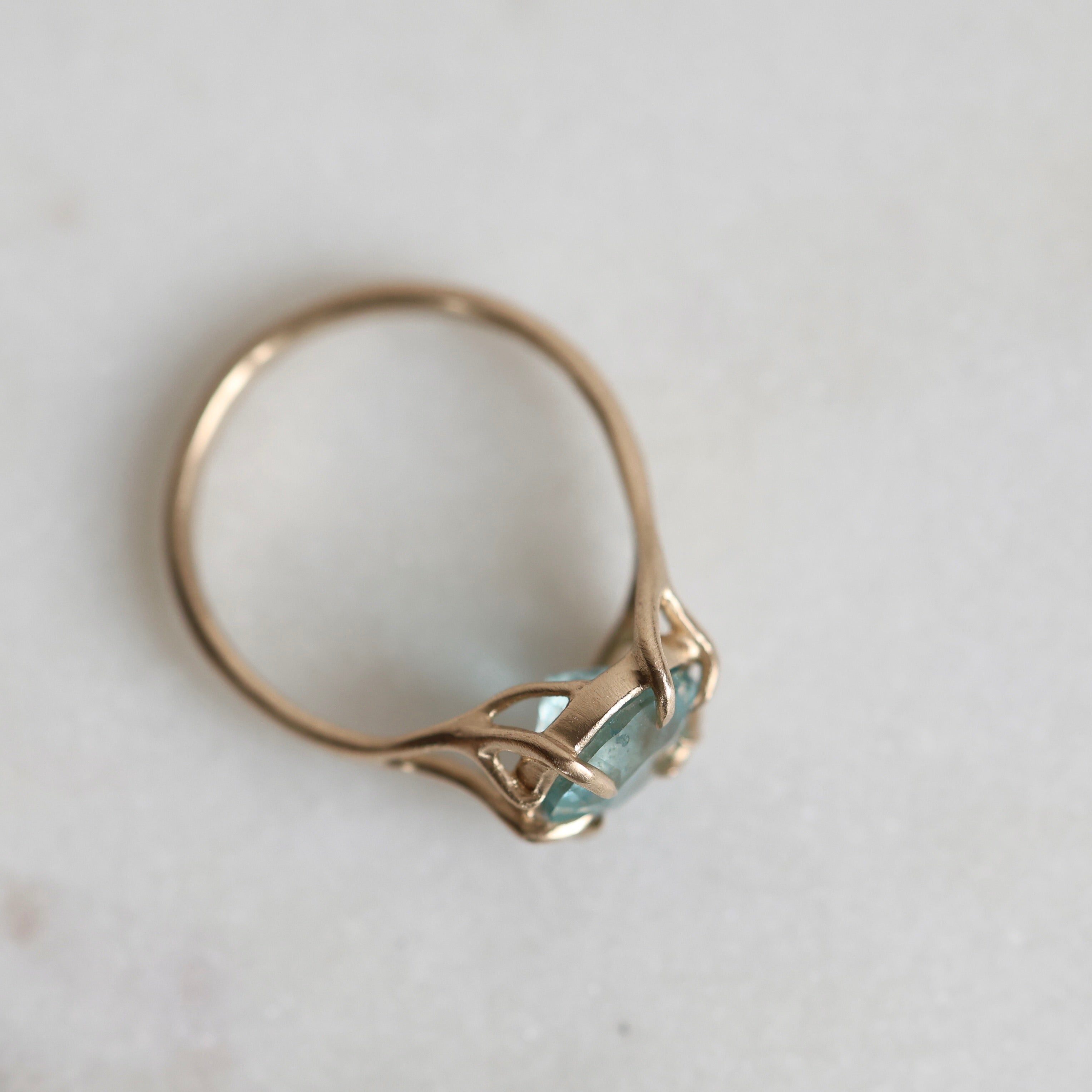 Gold ring with a green gemstone on a light gray background