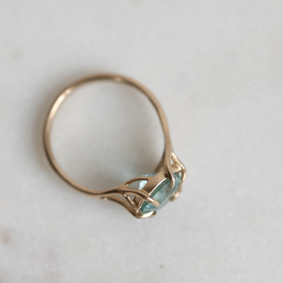 Gold ring with a green gemstone on a light gray background