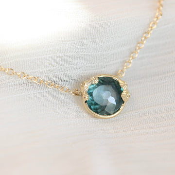 Necklace with a teal gemstone pendant on a white fabric background