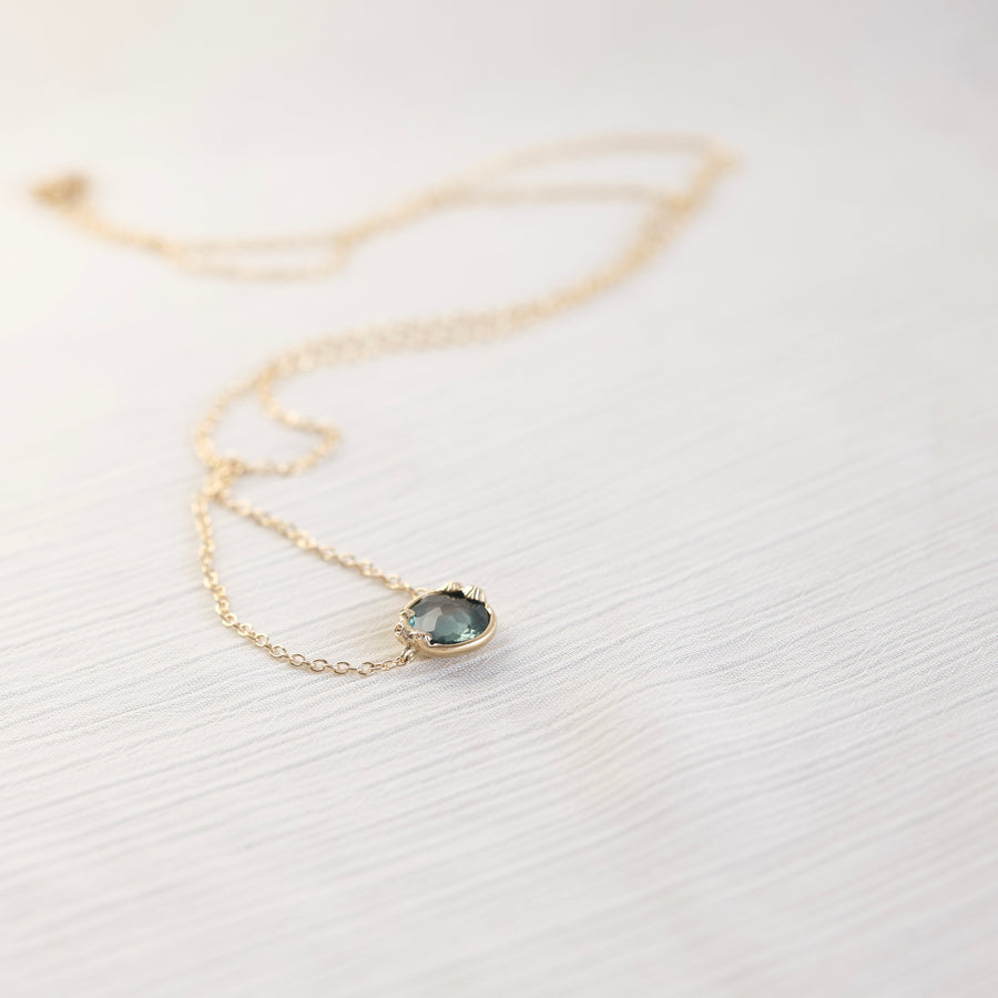 Necklace with a teal gemstone pendant on a white fabric background