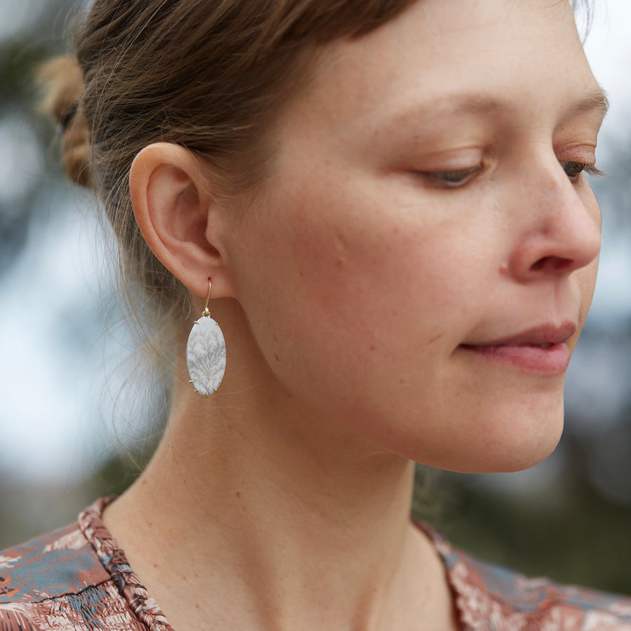white snowy dendritic agate drop earrings with gold prongs on person by hannah blount