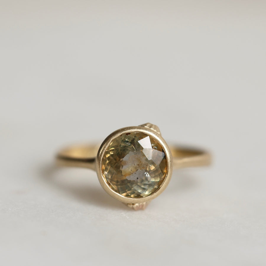 Gold ring with a gold sapphire on a light gray background